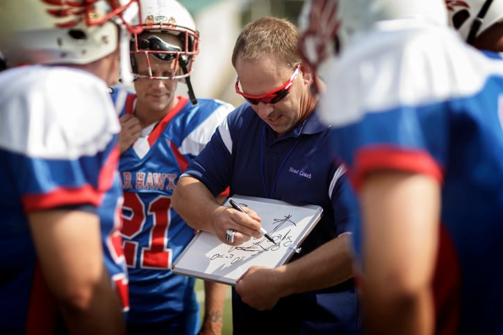 football coach drawing up a play on a whiteboard